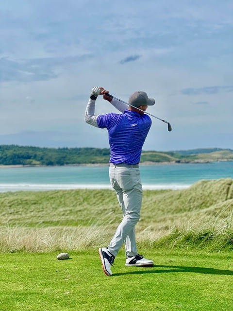 A golfer teeing off, wearing a breizh sports polo